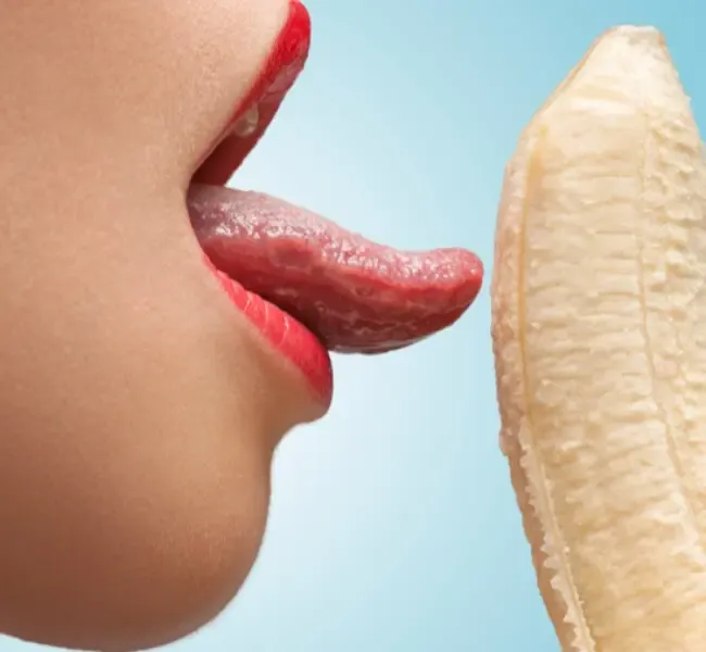 Escort Zunge leckt an einer Banane und denkt dabei an einen Penis