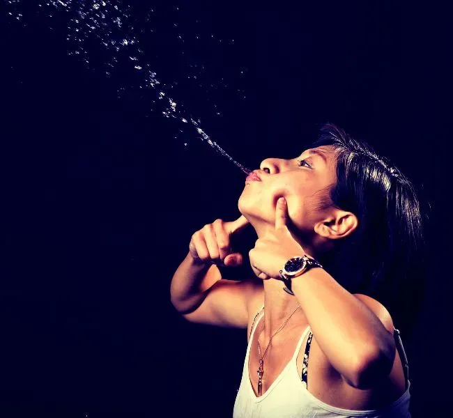 A woman spitting water out of her mouth