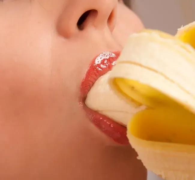 A woman with a banana in her mouth