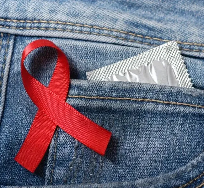 the red ribbon for solidarity with hiv positives on a pocket with a condom