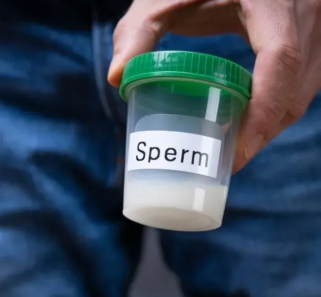 Ein Mann der sein Sperma in einem Plastikbecker hält
