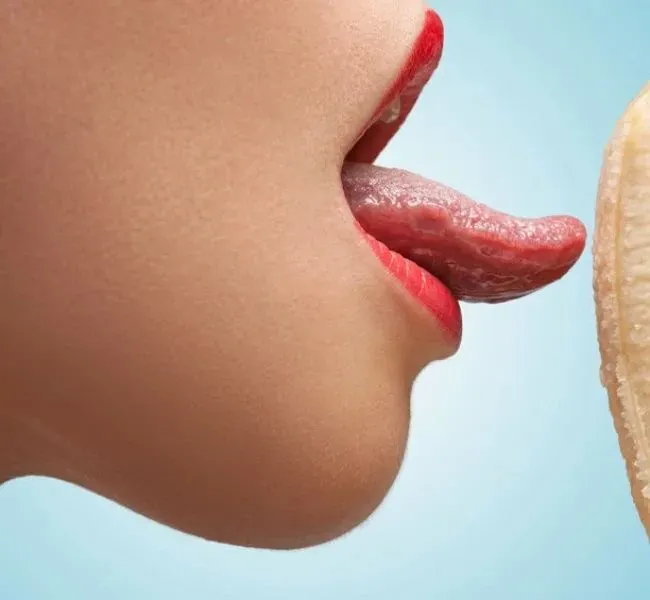 A woman licking a banana with her tongue