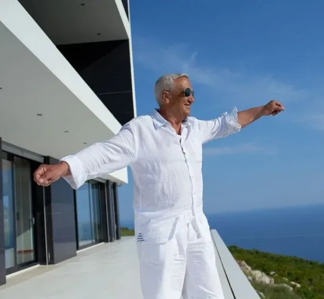 A sugardaddy stands on the terrace of his villa