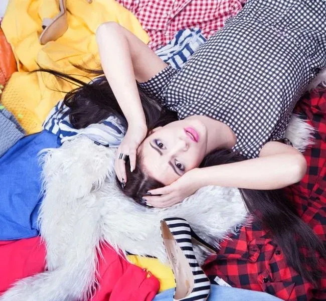 Escort lady lying on a mountain of clothes