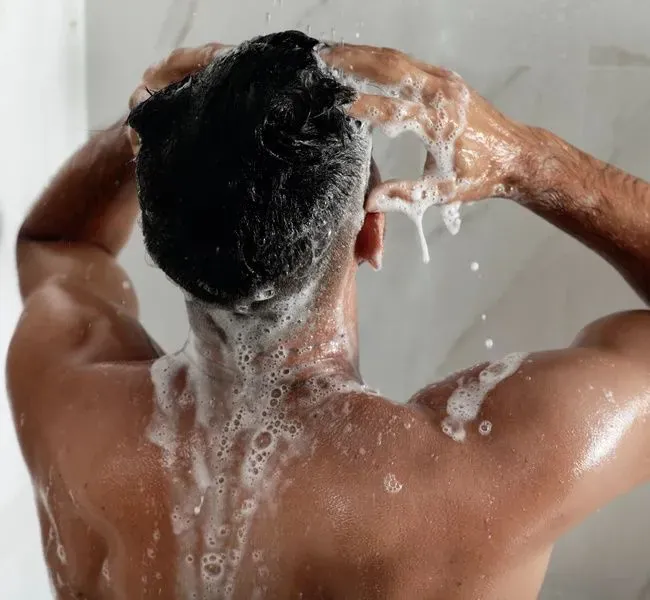 Ein Mann unter der Dusche mit Schaum